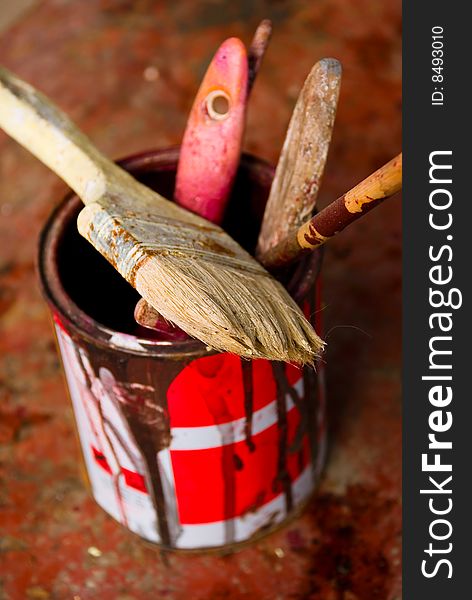 Used brushes in a dirty, rusted paint canister. Used brushes in a dirty, rusted paint canister