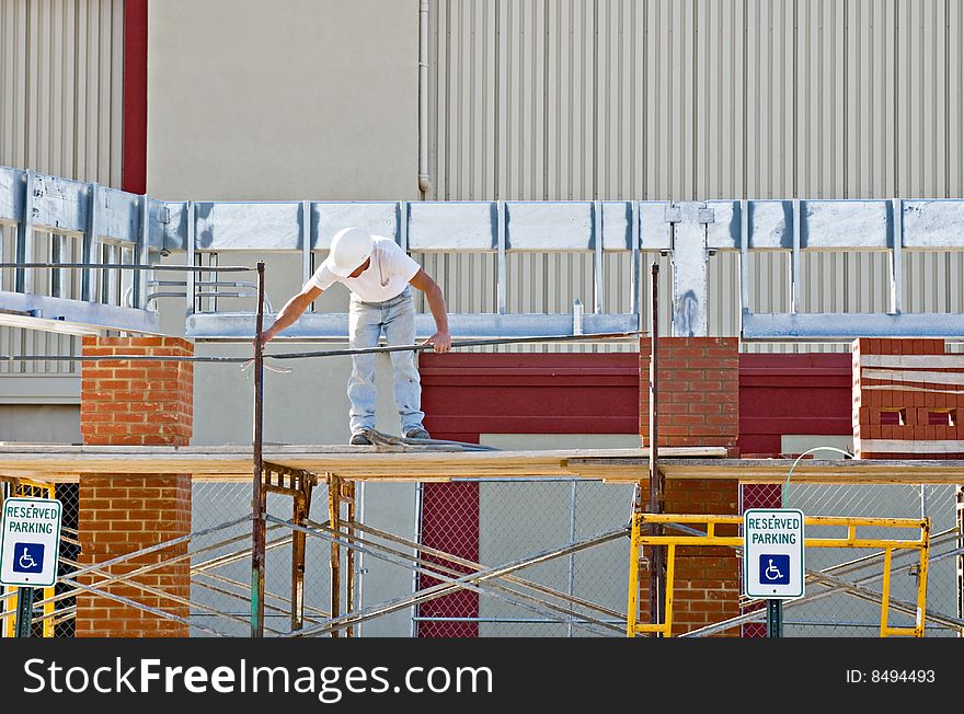 Consruction worker setting up scaffolding at construction site.