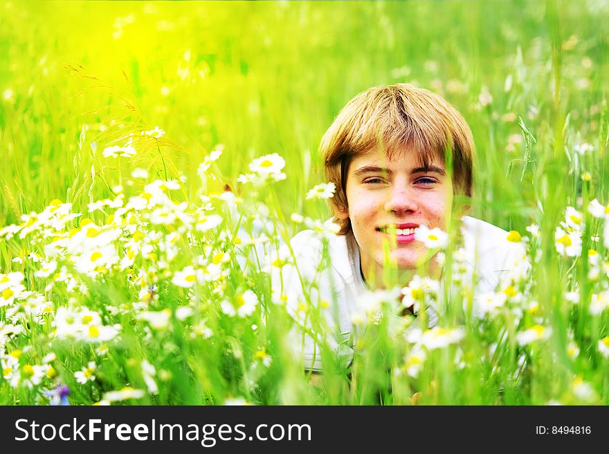 Happy summer. A smiling young boy lying in green grass
