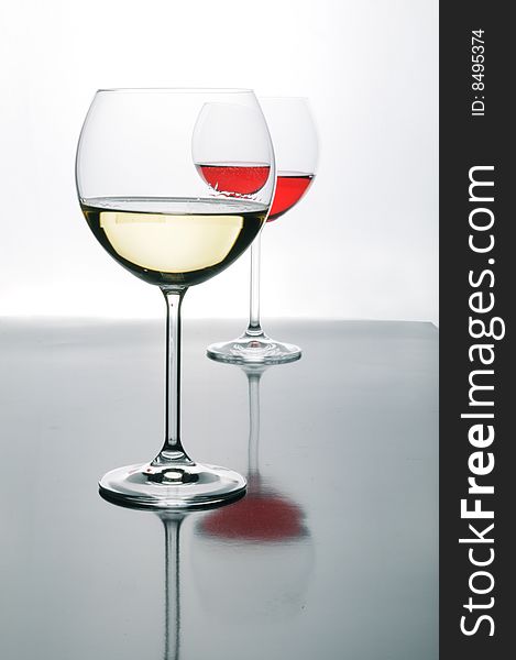 Two glasses of red and white wine on grey isolated on white with reflection
