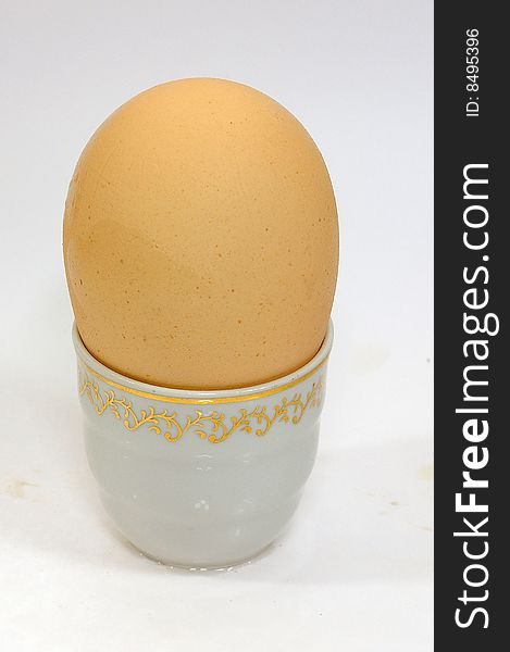 Egg of the hen dietetic yellow on porcelain stand and white background