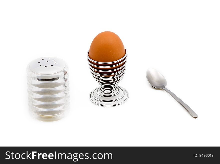 An egg on an eggcup next to a salt can and teaspoon