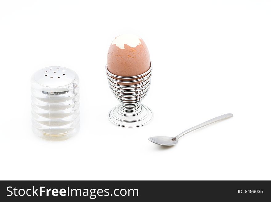 An eggcup with a pealed egg next to a salt can.