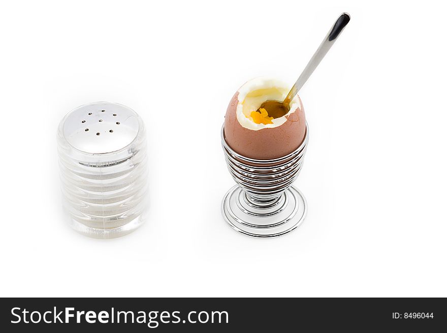 An egg on an eggcup next to a salt can, isolated on white