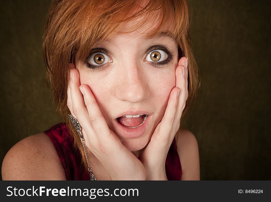 Shocked pretty young girl with red hair on a green background. Shocked pretty young girl with red hair on a green background