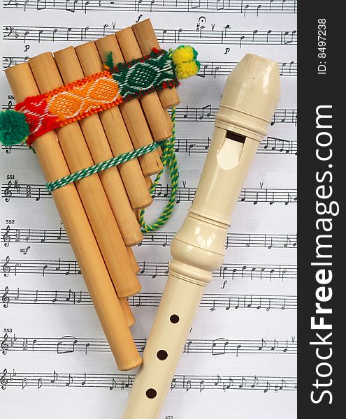 The Mexican pipe with a traditional ornament and a beige flute lay on the partita. The Mexican pipe with a traditional ornament and a beige flute lay on the partita