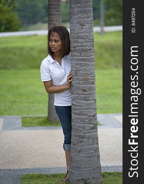 A female hiding behind a palm tree in the park. A female hiding behind a palm tree in the park.