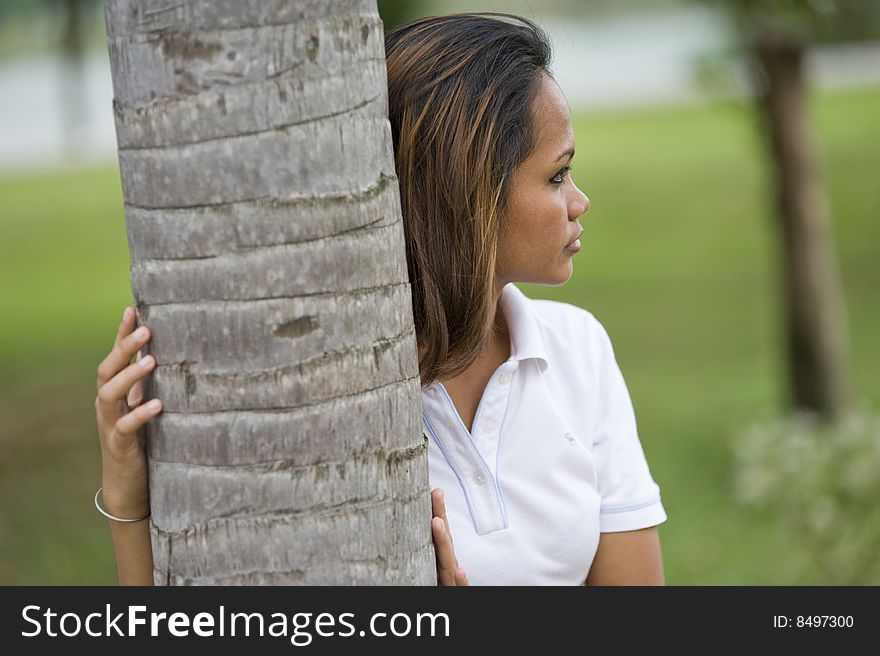 A female waiting behind a palm tree in the park. A female waiting behind a palm tree in the park.