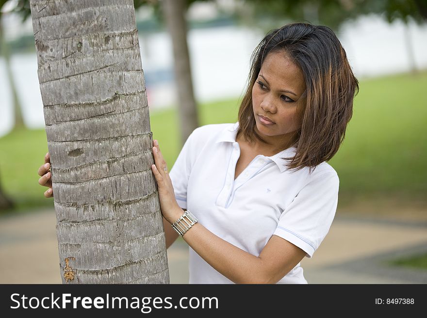 A female waiting behind a palm tree in the park looking to the left. A female waiting behind a palm tree in the park looking to the left.