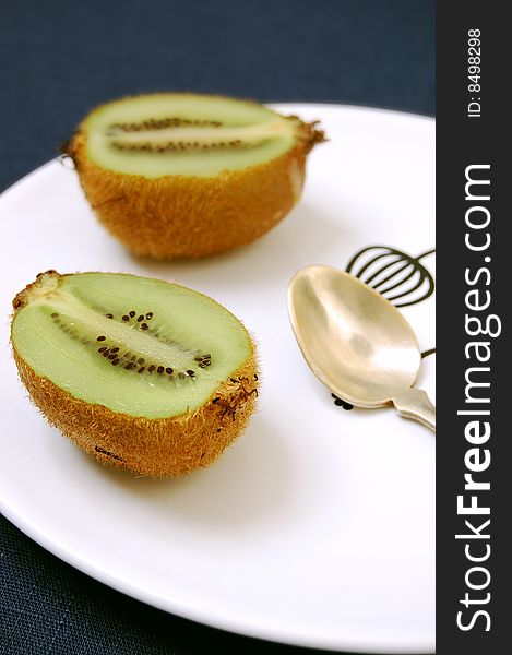 Two half kiwifruit on the white dessert-plate view from one side.