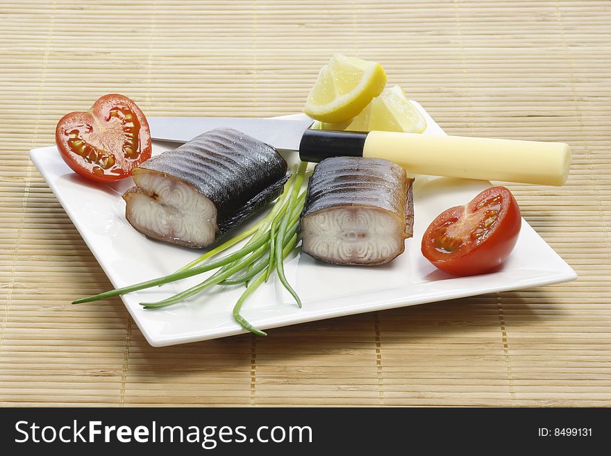 Pieces of smoked eel on a plate with garnish. Pieces of smoked eel on a plate with garnish