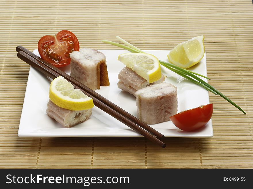 Pieces of smoked eel on a plate with garnish. Pieces of smoked eel on a plate with garnish