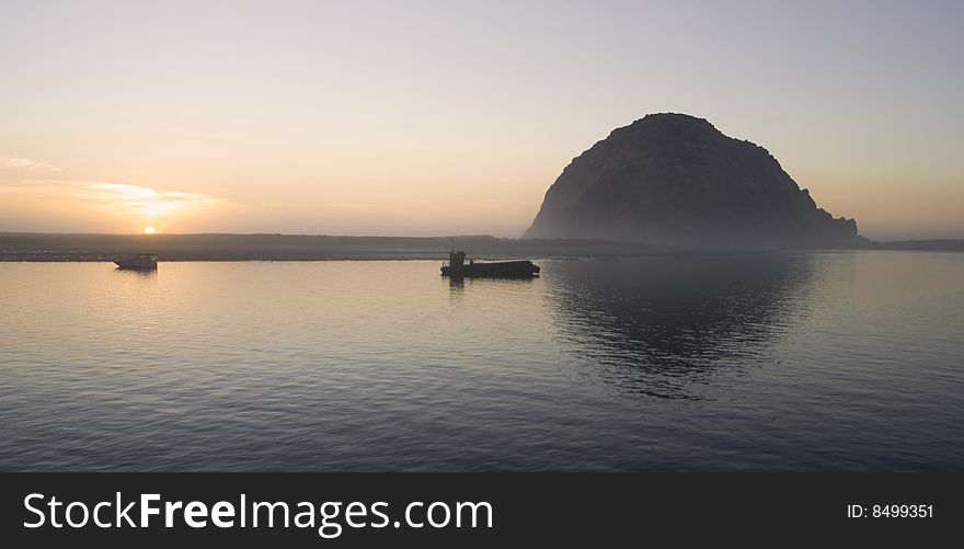 Morro Rock rests behind Morro Bay, California at sunset