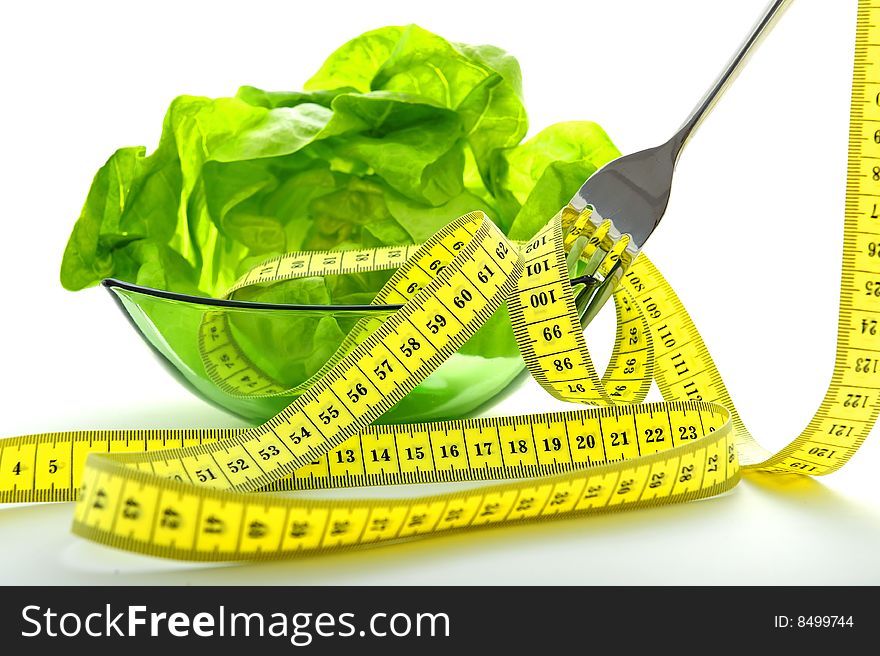 Green salad in bowl a fork and a tape measure. Green salad in bowl a fork and a tape measure