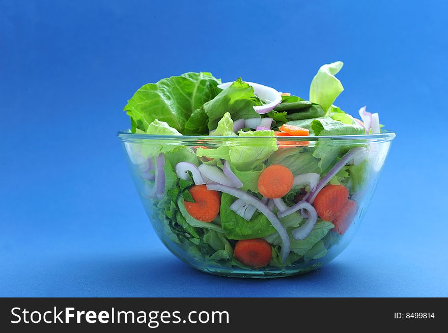 Assorted salad on bowl, on blue background