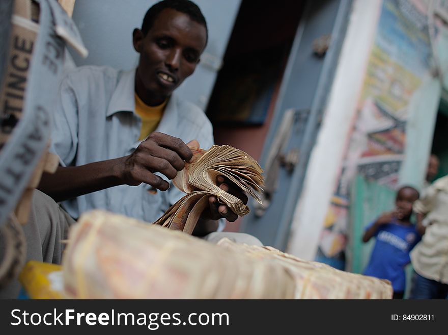 A money exchanger counts Somali shilling notes on the streets of the Somali capital Mogadishu. Millions of people in the Horn of Africa nation Somalia rely on money sent from their relatives and friends abroad in the form of remittances in order to survive, but it is feared that a decision by Barclays Bank to close the accounts of some of the biggest Somali money transfer firms – due to be announced this week - will have a devastating effect on the country and its people. According to the United Nations Development Programme &#x28;UNDP&#x29;, an estimated $1.6 billion US dollars is sent back annually by Somalis living in Europe and North America. Some money transfer companies in Somalia have been accused of being used by pirates to launder money received form ransoms as well as used by Al Qaeda-affiliated extremist group al Shabaab group to fund their terrorist activities and operations in Somalia and the wider East African region. AU/UN IST PHOTO / STUART PRICE. A money exchanger counts Somali shilling notes on the streets of the Somali capital Mogadishu. Millions of people in the Horn of Africa nation Somalia rely on money sent from their relatives and friends abroad in the form of remittances in order to survive, but it is feared that a decision by Barclays Bank to close the accounts of some of the biggest Somali money transfer firms – due to be announced this week - will have a devastating effect on the country and its people. According to the United Nations Development Programme &#x28;UNDP&#x29;, an estimated $1.6 billion US dollars is sent back annually by Somalis living in Europe and North America. Some money transfer companies in Somalia have been accused of being used by pirates to launder money received form ransoms as well as used by Al Qaeda-affiliated extremist group al Shabaab group to fund their terrorist activities and operations in Somalia and the wider East African region. AU/UN IST PHOTO / STUART PRICE.