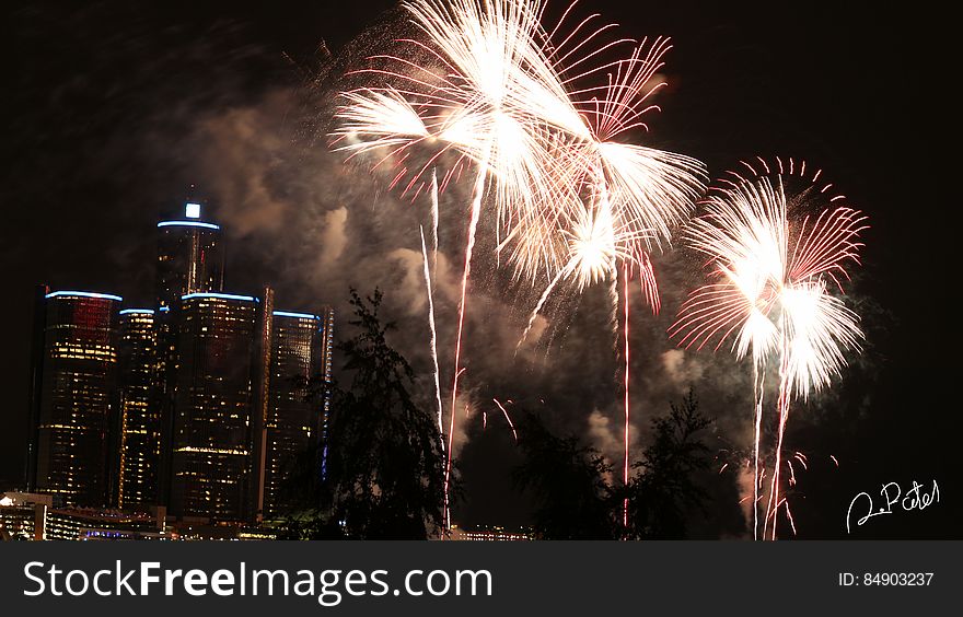 Fireworks display against city skyline illuminated at night. Fireworks display against city skyline illuminated at night.