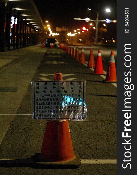 Orange traffic cones on side of street at night. Orange traffic cones on side of street at night.