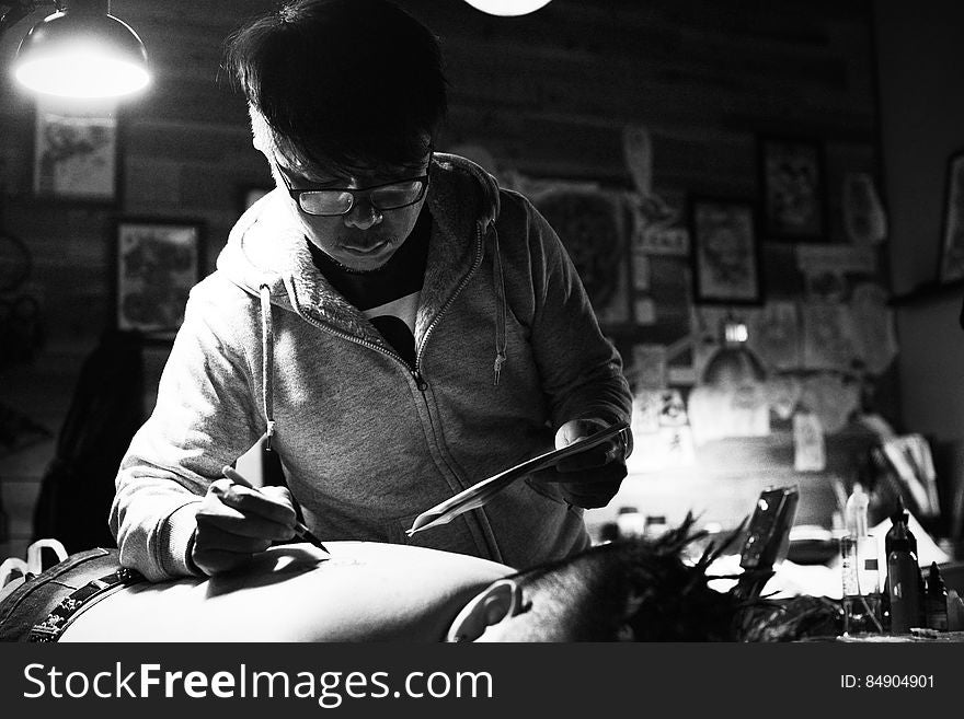 Black and white portrait of a tattoo artist working on man's back. Black and white portrait of a tattoo artist working on man's back.