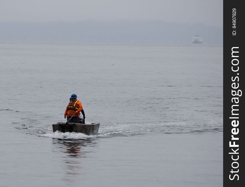 Man in wooden boat on water in fog. Man in wooden boat on water in fog.