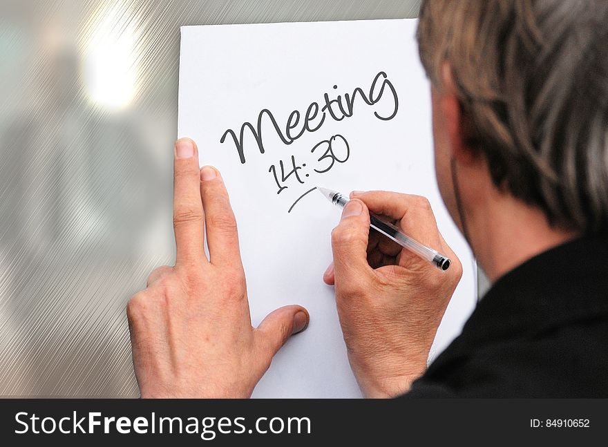 A man writing a note about meeting. A man writing a note about meeting.