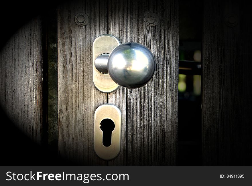 A close up of a knob and a keyhole on a wooden door. A close up of a knob and a keyhole on a wooden door.