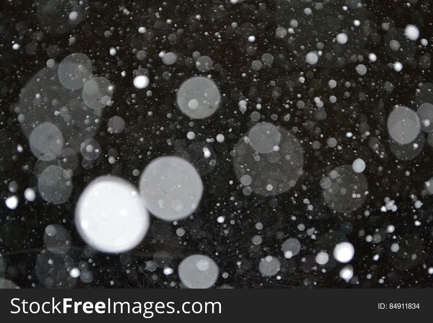 A close up shot of rain drops on a black background.