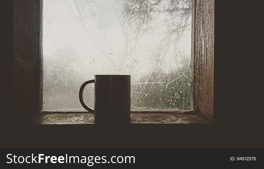 A mug sitting on a window sill. A mug sitting on a window sill.