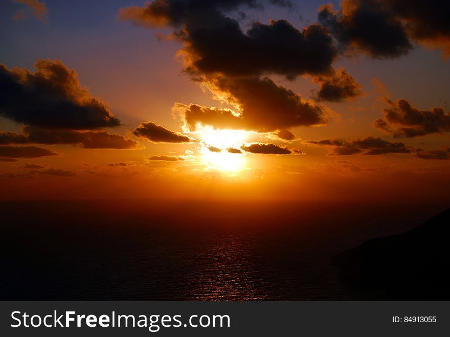 Cloudscape over calm sea with bright orange sunset. Cloudscape over calm sea with bright orange sunset.