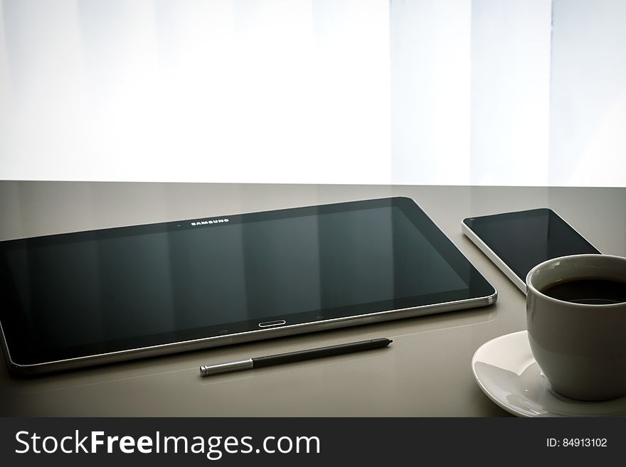 Tablet, smartphone, pencil and a cup of coffee on a table. Tablet, smartphone, pencil and a cup of coffee on a table.