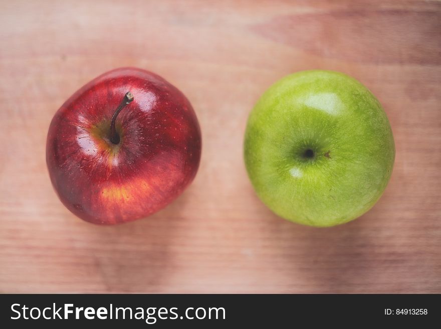 A red and a green apple on a wooden background. A red and a green apple on a wooden background.