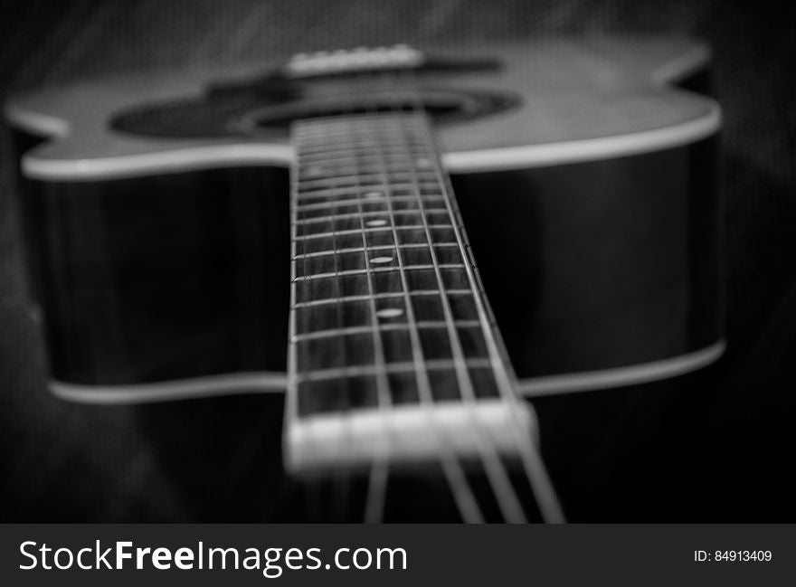 A black and white close up of an acoustic guitar.