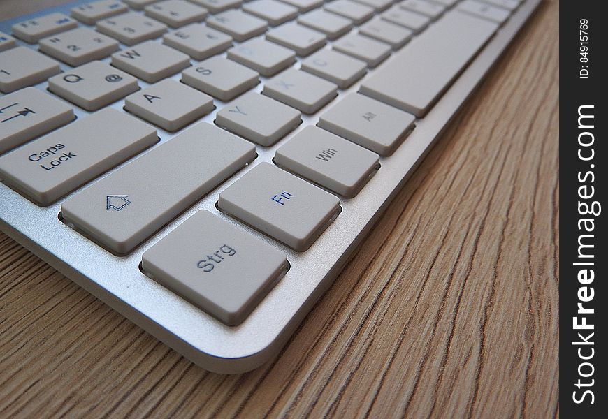 White Computer Keyboard On Brown Wooden Table