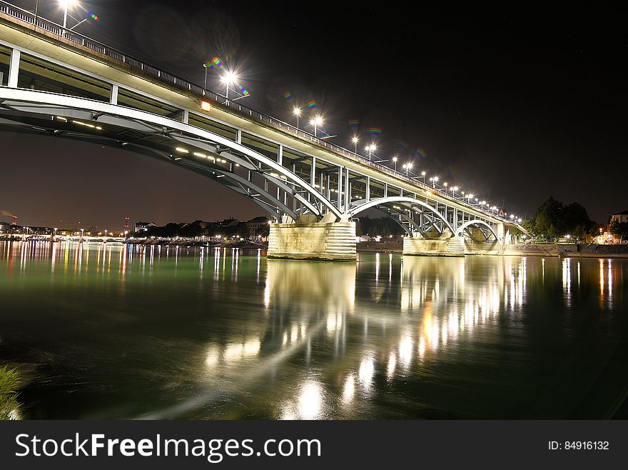 A bridge in the night with lights reflecting from the water. A bridge in the night with lights reflecting from the water.