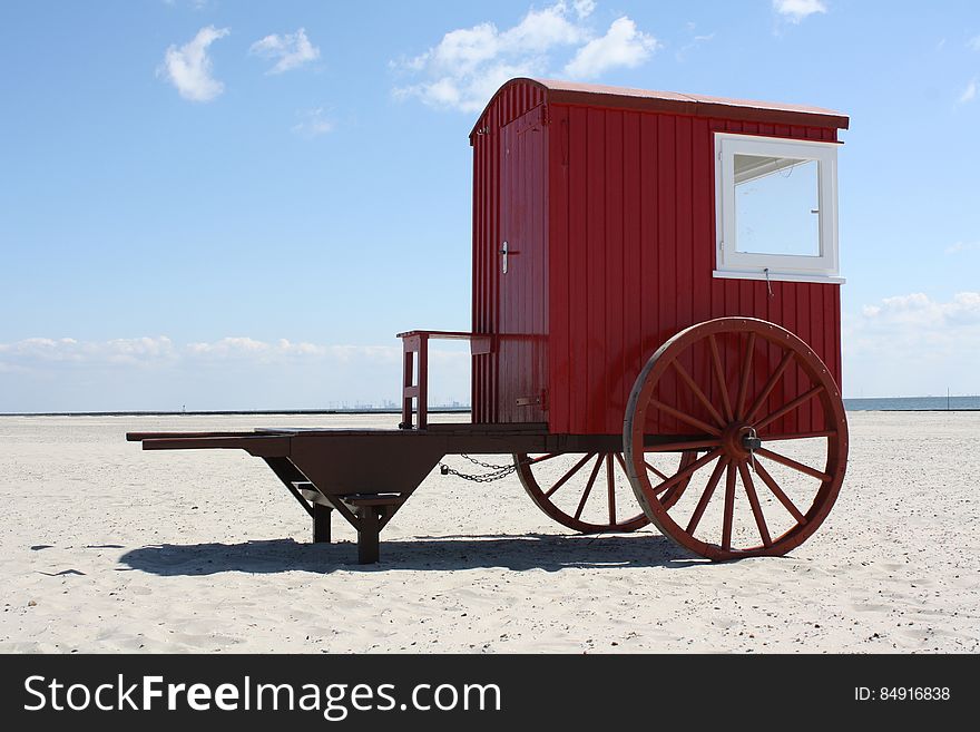 Red painted vintage wooden wagon on beach.