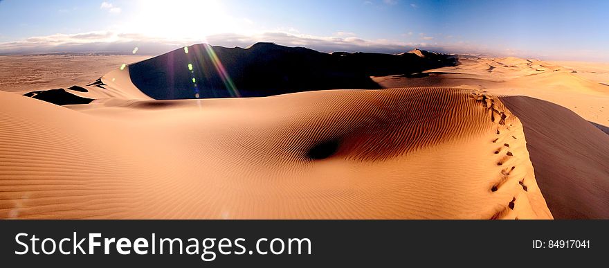 As far as they eye can see sand dunes in the desert with the sun low in sky casting deep shadows.