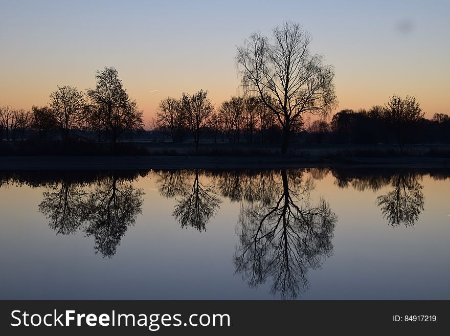 Reflection Of Silhouette Trees In Lake Against Sky At Sunset