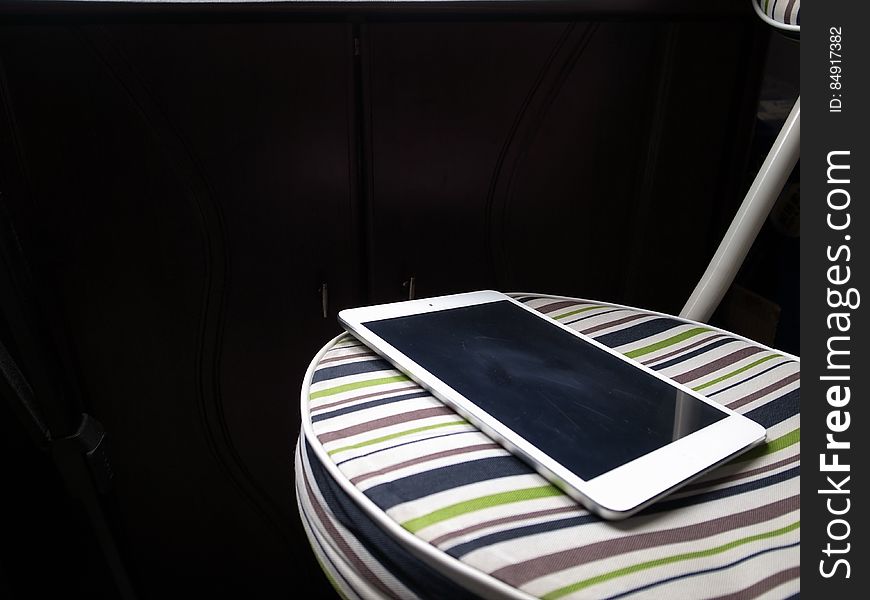 A close up of an Apple iPad on a striped chair. A close up of an Apple iPad on a striped chair.