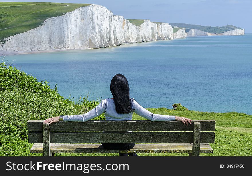 Woman Sitting on Deck Chair by Sea