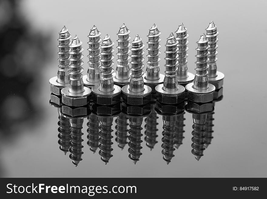A set of iron bolts reflecting on a glassy surface. A set of iron bolts reflecting on a glassy surface.