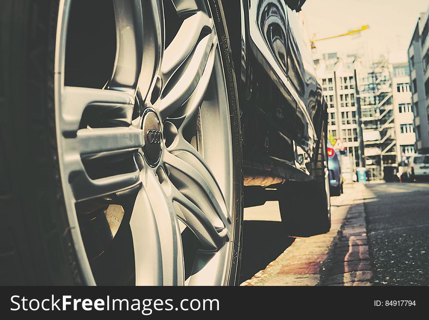 Low angle view of wheels of modern motor car parked on city street. Low angle view of wheels of modern motor car parked on city street.