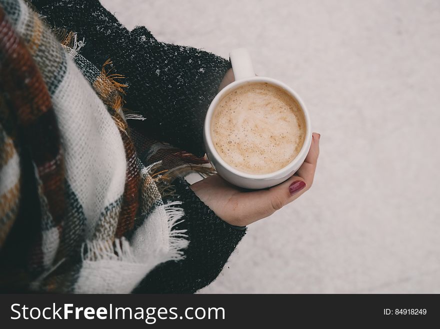 A woman holding a cup of coffee outdoors in the winter. A woman holding a cup of coffee outdoors in the winter.