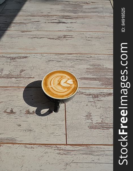 A cup of coffee with latte art on sunny day.