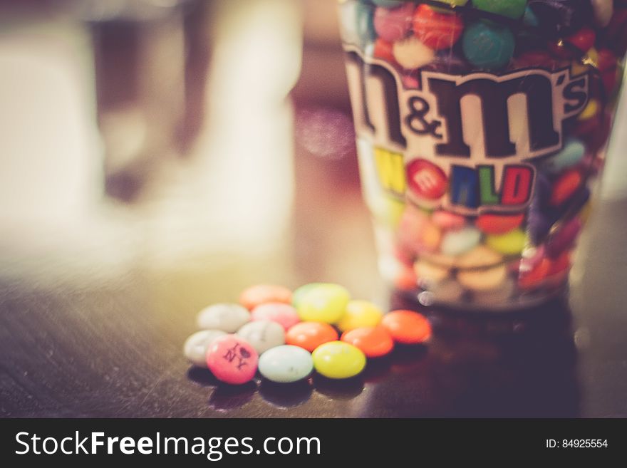 Close up of cup of M&M candies on wooden table.