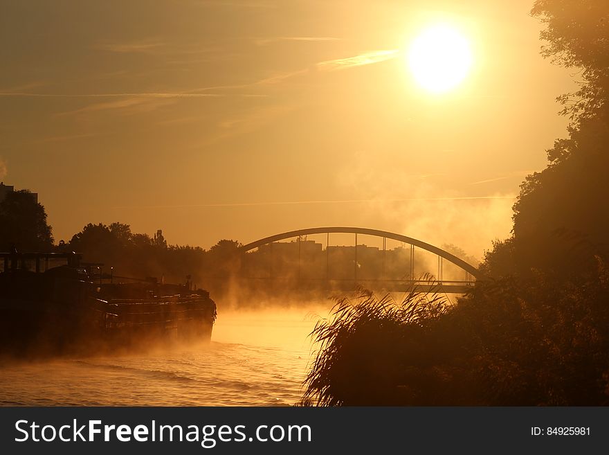 Sunset And Bridge Over River