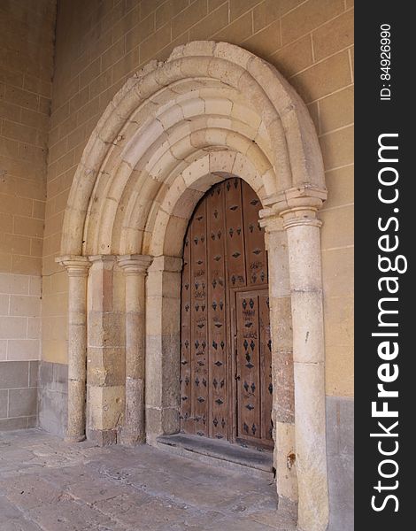 Wooden antique door under stone arches outside building. Wooden antique door under stone arches outside building.