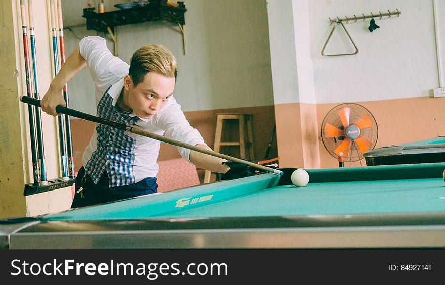 Asian man shooting pool in hall.