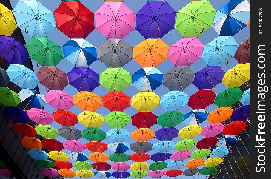 Yellow Blue Red Pink Purple Green Multicolored Open Umbrellas Hanging on Strings Under Blue Sky