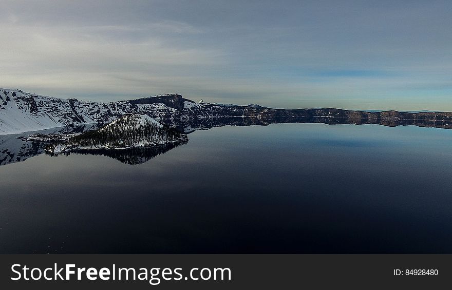 Snow covered landscape reflecting on calm lake. Snow covered landscape reflecting on calm lake.