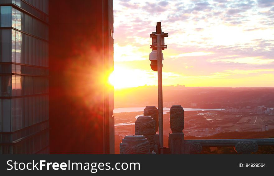 A view of city buildings with sun setting in the horizon. A view of city buildings with sun setting in the horizon.